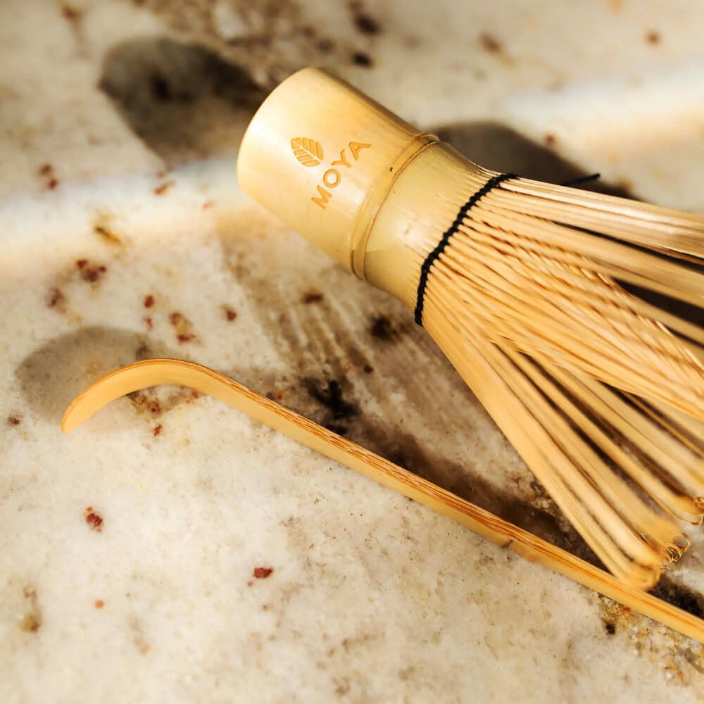 Világos bambusz matcha teakanál közelről, bambusz habverő mellett, világos márvány felületen.