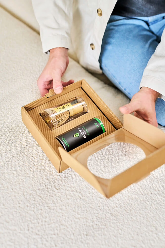 Matcha tea és bambusz habverő szett, kézben tartott MOYA matcha dobozzal nyitott ajándékdobozban