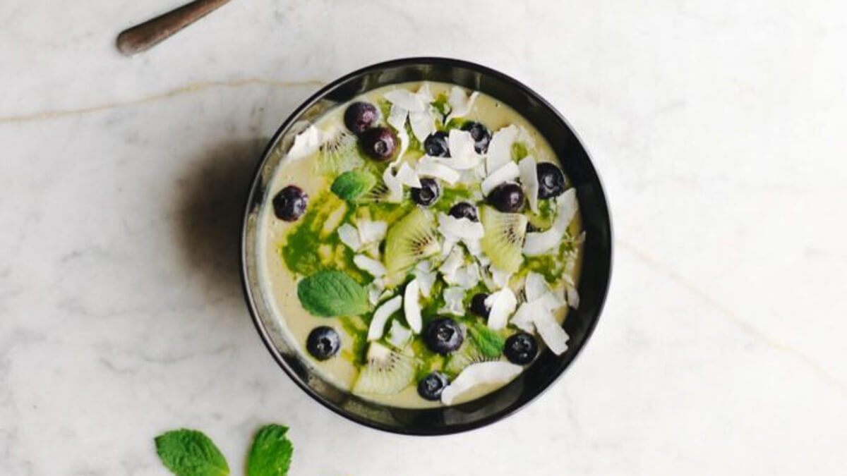 Matcha Smoothie tál kiwi-karikákkal, áfonyával és kókuszchipsszel, felülnézetből
