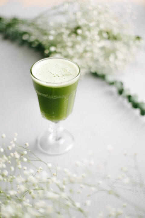 Matcha alma fröccs talpas pohárban, halvány habréteggel, világos nyári háttéren