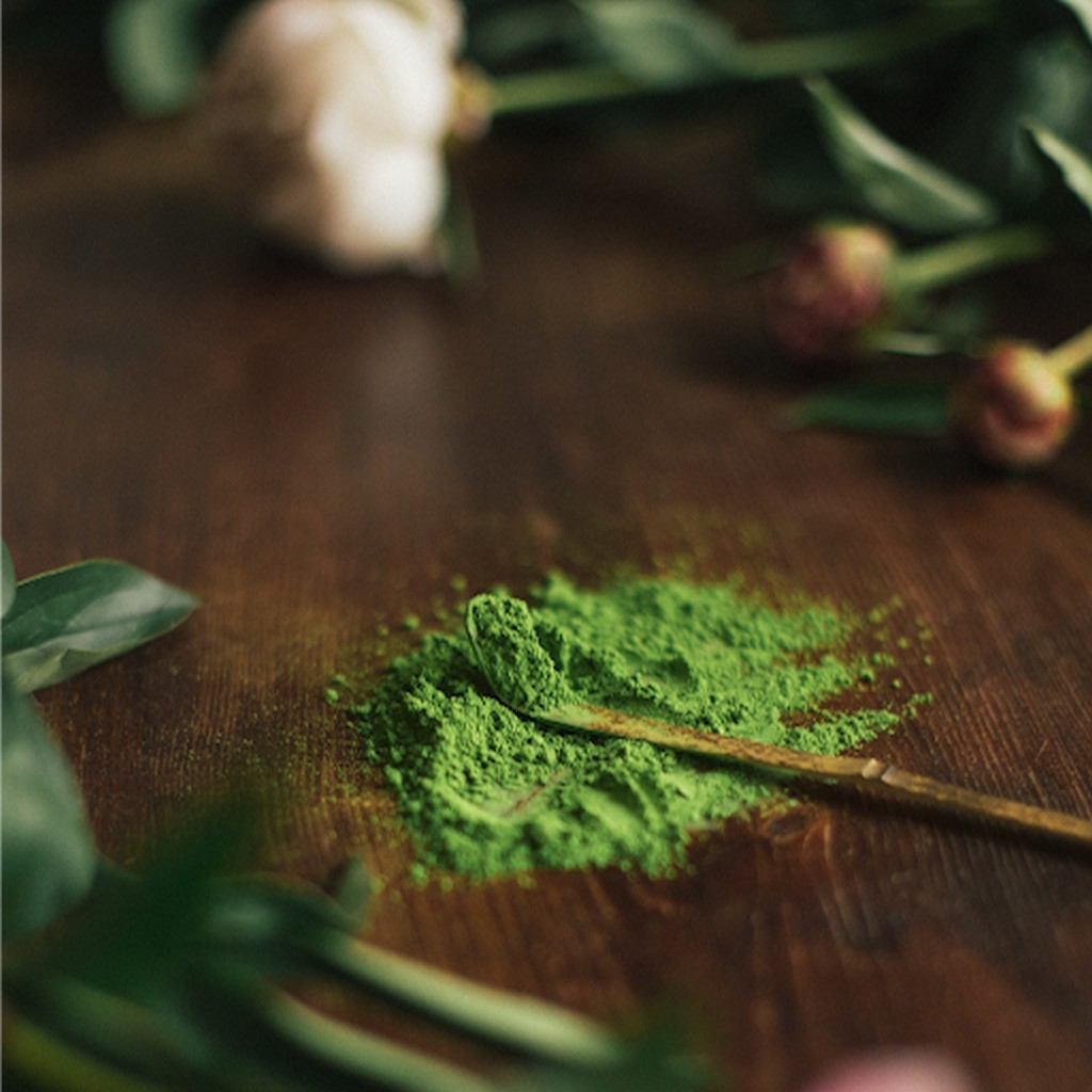 Matcha por egy bambusz teáskanálon, élénk zöld színnel