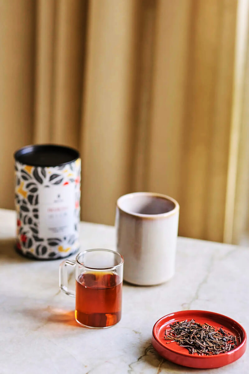 Moya Hojicha organikus japán zöld tea lifestyle fotó üveg bögrével, csészével és pörkölt levelekkel.