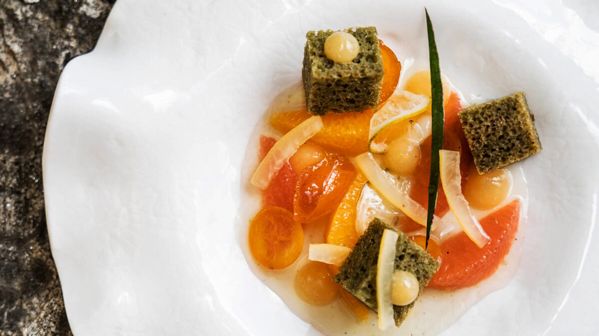 Matcha torta kockák citrusokkal és sziruppal fehér tányéron tálalva