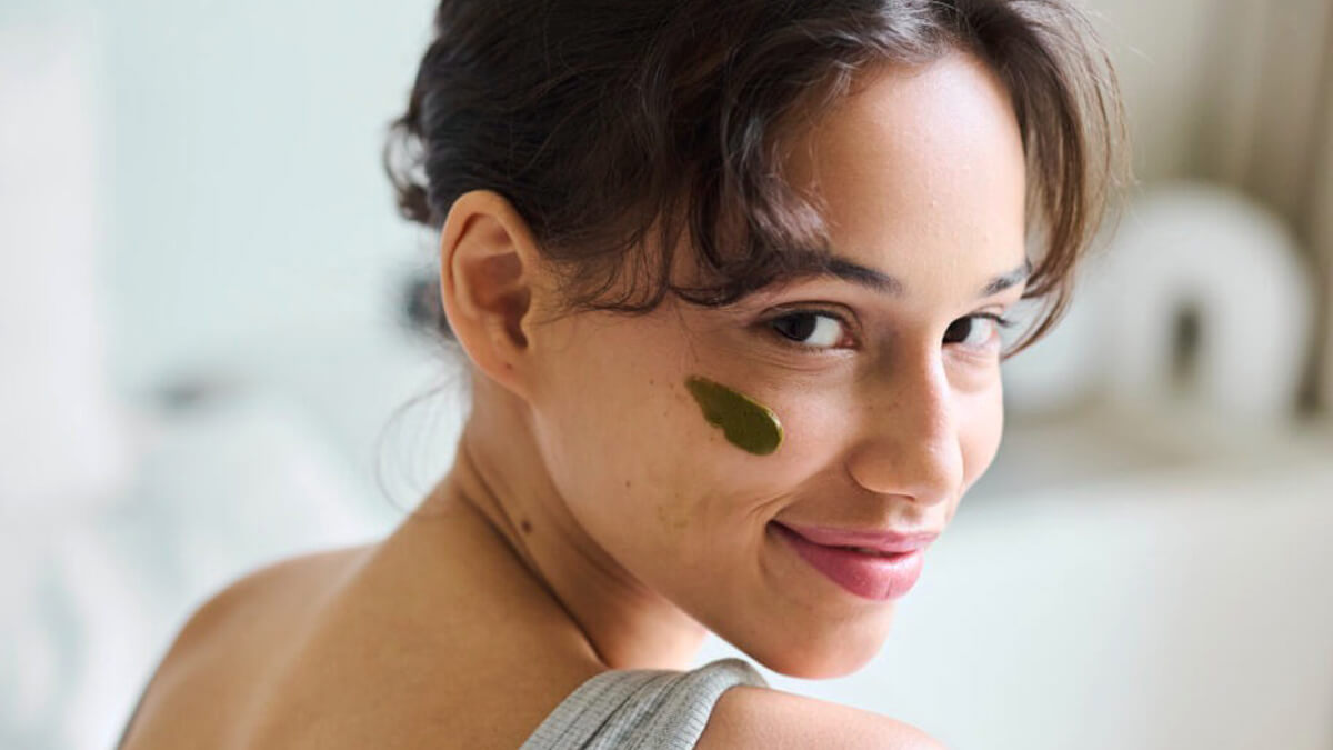 Nő arcán zöld pakolás közelről, otthoni bőrápolási jelenet a matcha és zöld tea bőrre témájához.