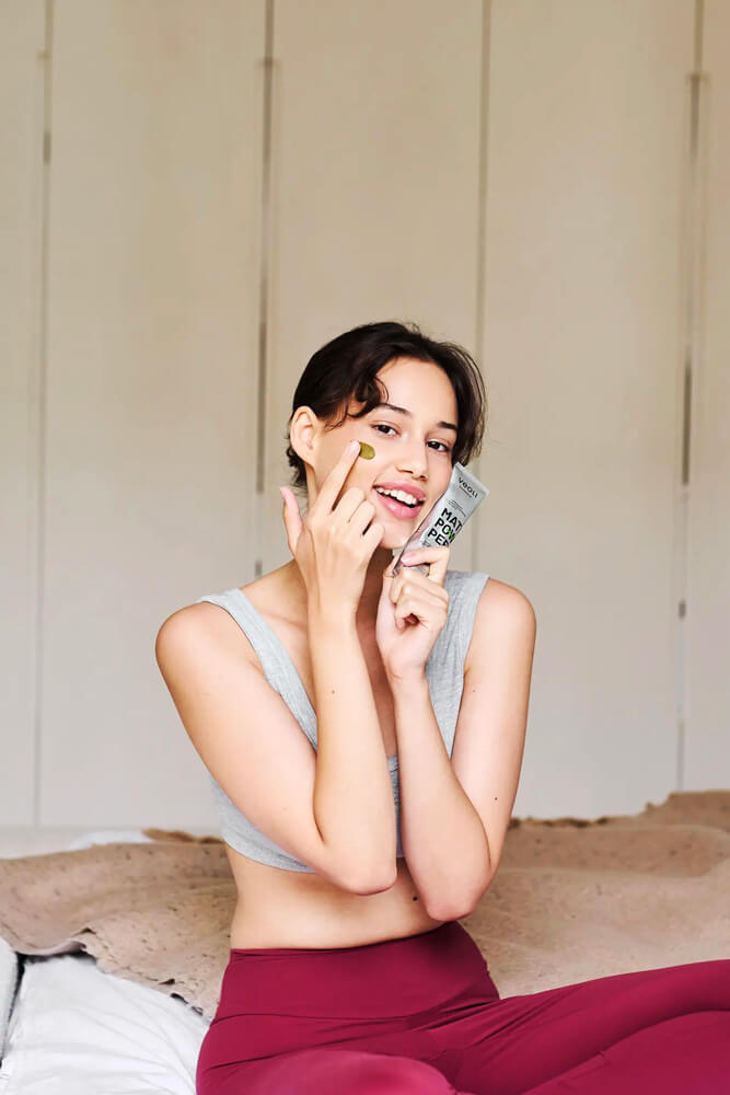 Nő zöld pakolással az arcán, kezében tubussal, lifestyle illusztráció a matcha és zöld tea bőrre cikkhez.