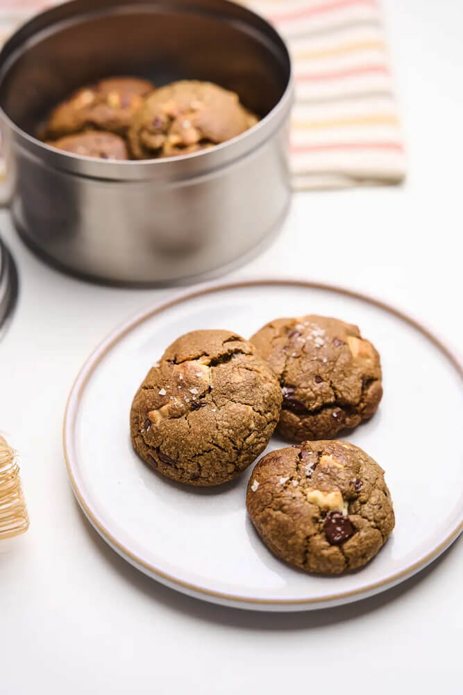Tányérra tálalt hojicha kekszek, háttérben fémdobozos adag