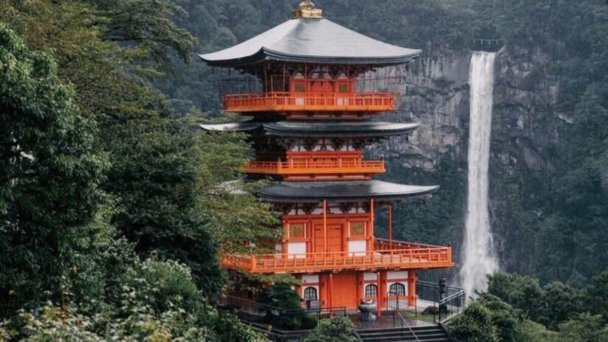 Teaism a matcha világában: narancsszínű japán pagoda és magas vízesés zöld, ködös hegyoldalban.