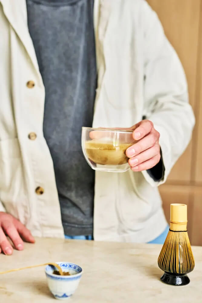 Hojicha por elkészítés chasennel Hojicha por elkészítése üvegpohárban, kézben tartott itallal és bambusz ecsettel