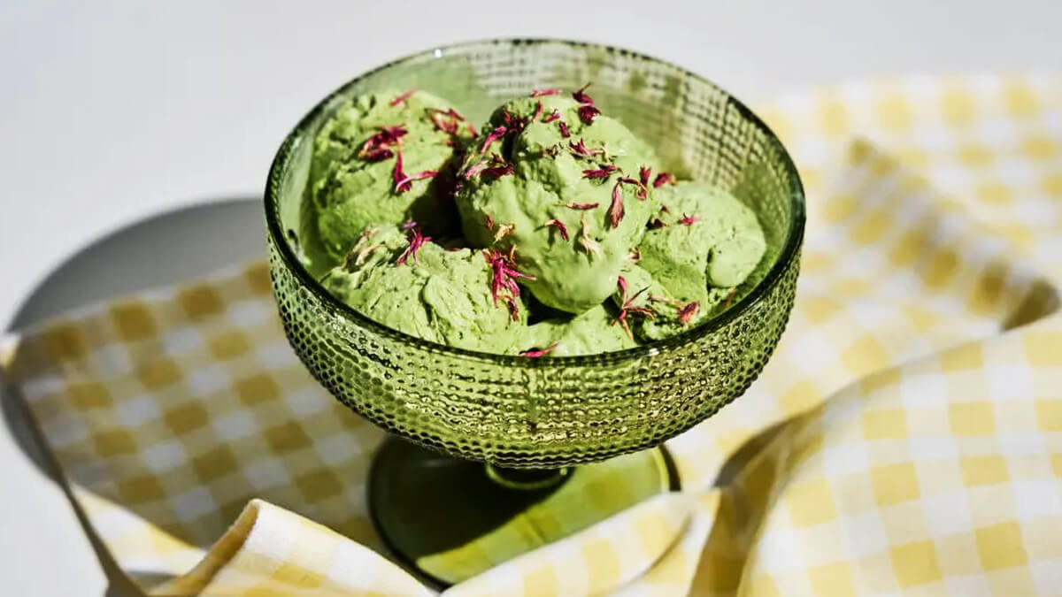 Matcha jégkrém recept fagylaltgép nélkül, zöld desszertkehelyben, piros szirmokkal és kanállal