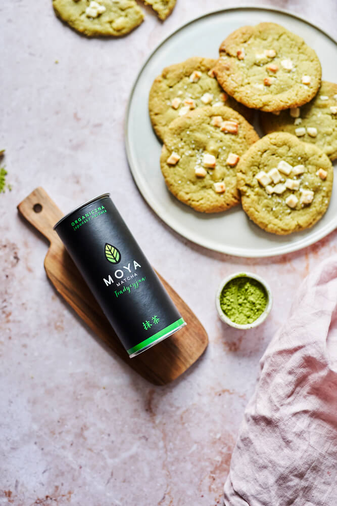 Matcha süti fehér csokoládéval, MOYA Matcha Traditional csomagolással és matcha porral lifestyle fotón.