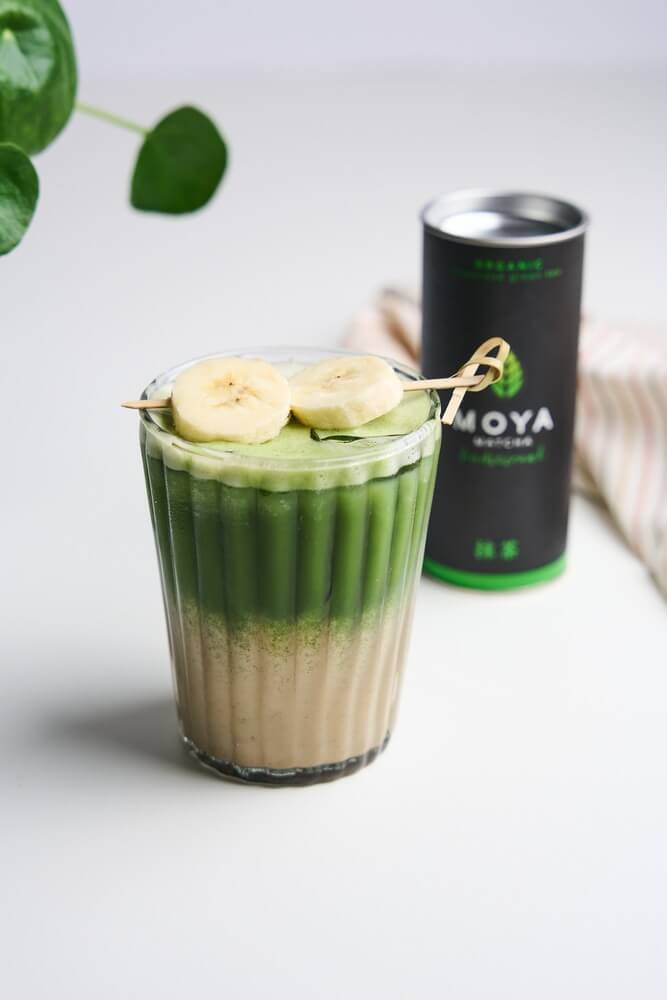 Banana bread matcha banánkarikákkal díszítve, mellette Moya matcha doboz