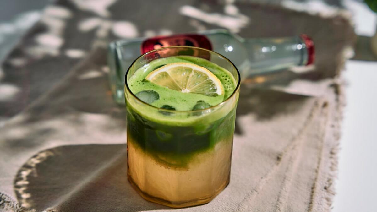 Matcha gyömbér tonik Rétegzett matcha gyömbér tonik pohárban jéggel és citrommal, felül élénkzöld matcha réteggel