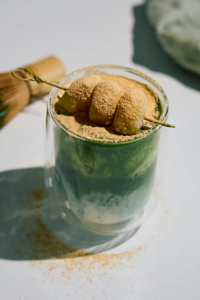 Matcha kinako krém magas pohárban jéggel, a tetején habos, pörkölt szójalisztes tejszínhabbal