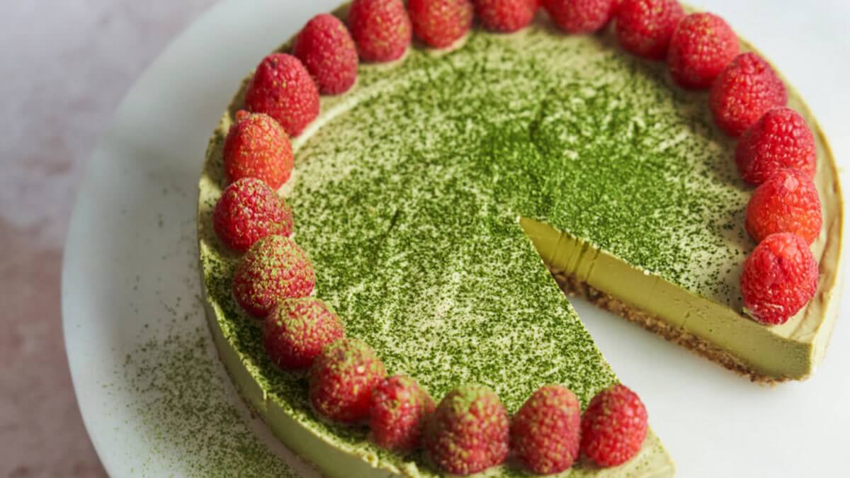Sütés nélküli vegán matcha sajttorta Sütés nélküli vegán matcha sajttorta friss málnával és eperrel díszítve, felülnézetből