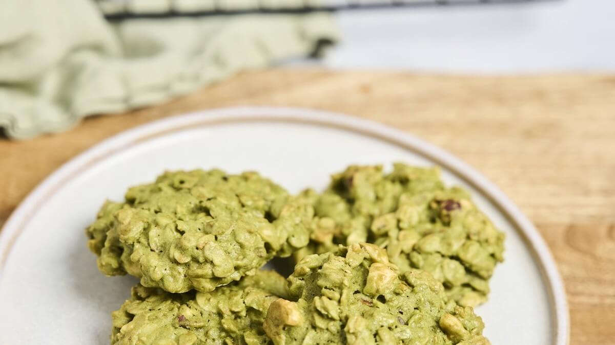 Matchás zabkeksz frissen sütve Matchás zabkekszek tányéron, a háttérben hűtőrács és frissen felvert matcha tea