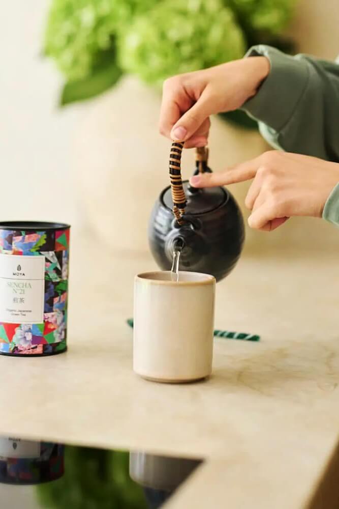 Matcha tea reggeli fókuszhoz és nyugodt rituáléhoz Fiatal nő matcha italt tart a kezében világos, nyugodt környezetben, reggeli fókuszhoz
