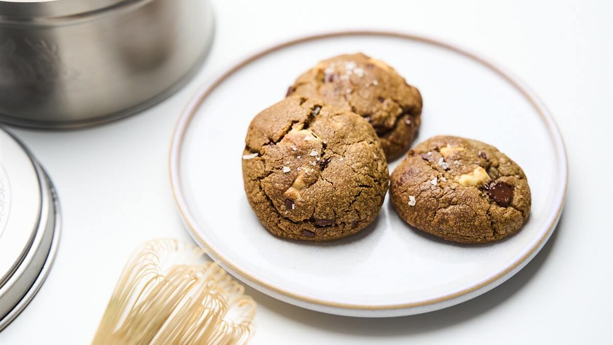 Hojicha keksz recept Hojicha kekszek tányéron, fémdobozzal és bambusz habverővel
