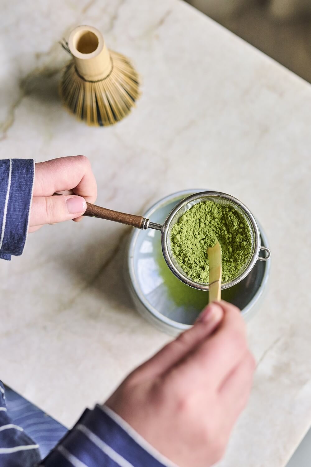 Matcha adagolása chashakuval Matcha por adagolása chashakuval, szitán át a tálba.